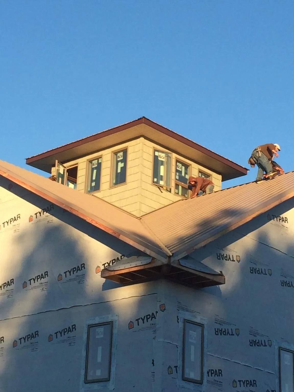 Roofers working around a rooftop cupola on a new metal roof at sunset — Roof Waterproofing in Linwood by Roofing Brothers